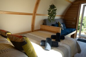Ein gemütliches, kleines Schlafzimmer mit einem Etagenbett, einer hängenden Pflanze und Blick durch eine Glastür.