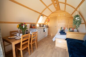 Cozy living space with a vaulted ceiling, dining area, compact kitchenette, and a comfortable bed.