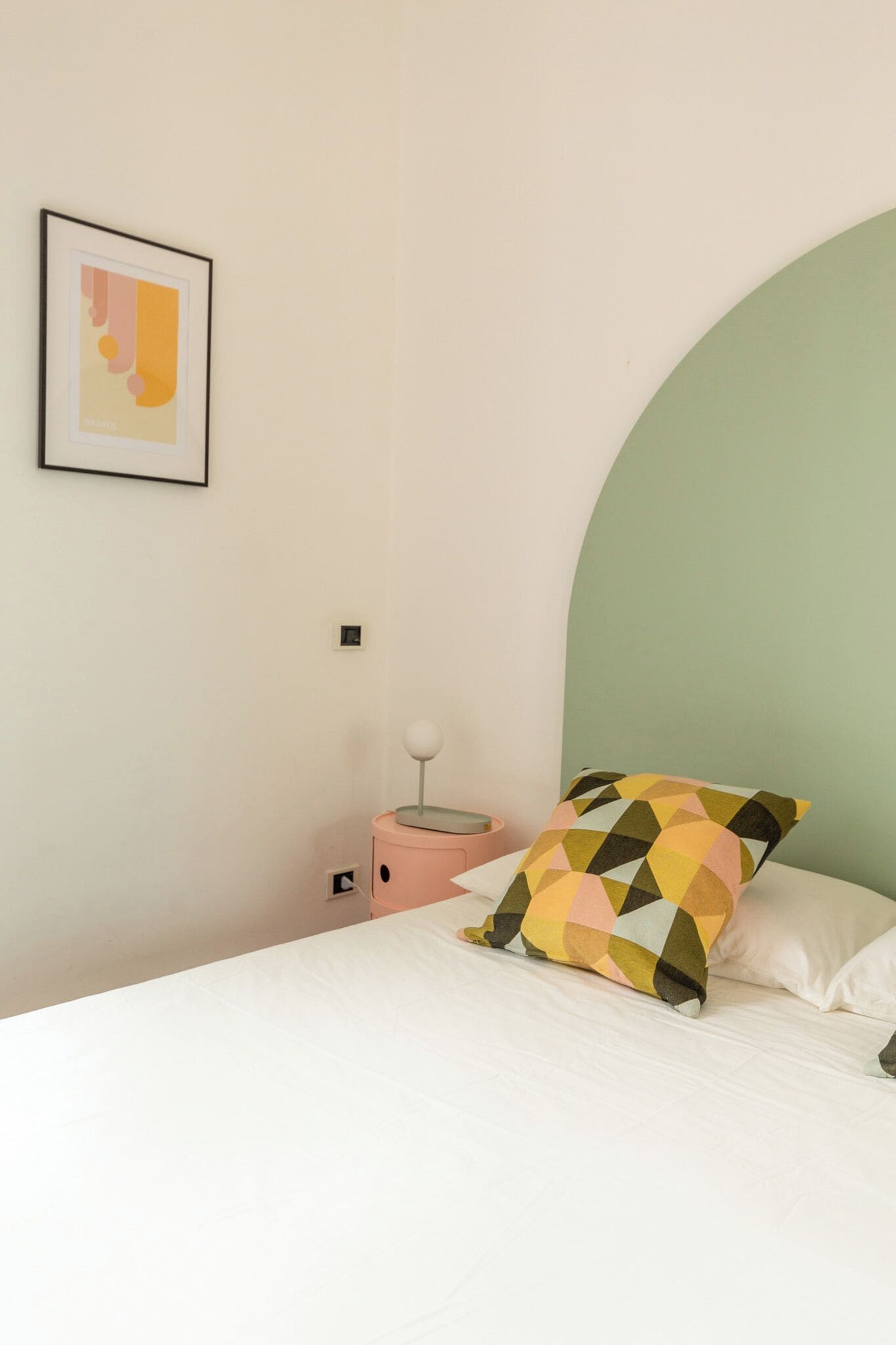 Ein Schlafzimmer mit Bett, Nachttisch, Lampe und einem gerahmten Bild an der Wand.