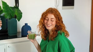 Eine Person sitzt an einem Holztisch mit einer Schüssel Schokoladenstückchen und einer Avocado.