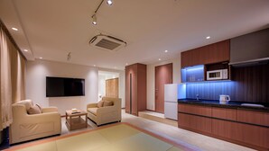A modern hotel room with a living area, a kitchen, and a television. - COCOYO HOTEL Otsuka (Tokyo)