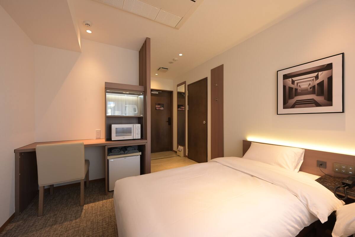 Une chambre d’hôtel avec un lit, un bureau et une armoire.