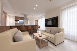 Ein modernes Wohnzimmer mit einer Sofagarnitur, einem Couchtisch und einem Fernseher.