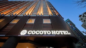 The exterior of the Cocoyo Hotel with a modern design, featuring a prominent illuminated sign and vertical lines on the facade. - COCOYO HOTEL Otsuka (Tokyo)