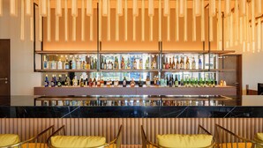 A bar area with multiple shelves of bottles, a marble countertop, and yellow upholstered chairs. - COCOYO HOTEL Otsuka (Tokyo)