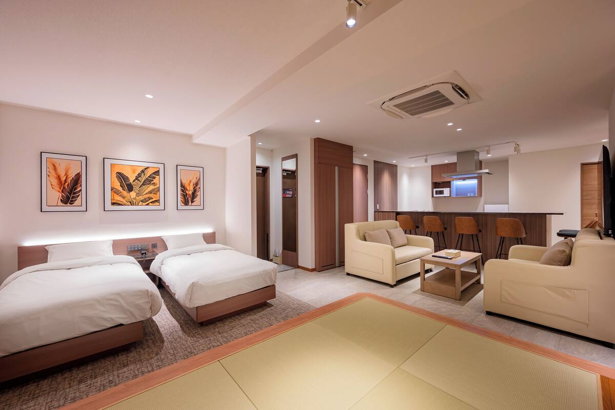 Une chambre d’hôtel avec deux lits, un canapé, une petite table et un téléviseur.