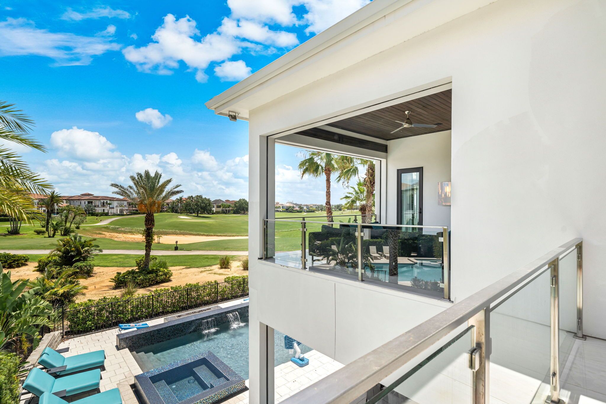 A modern building with a pool area, a view of a golf course, and a clear sky.
