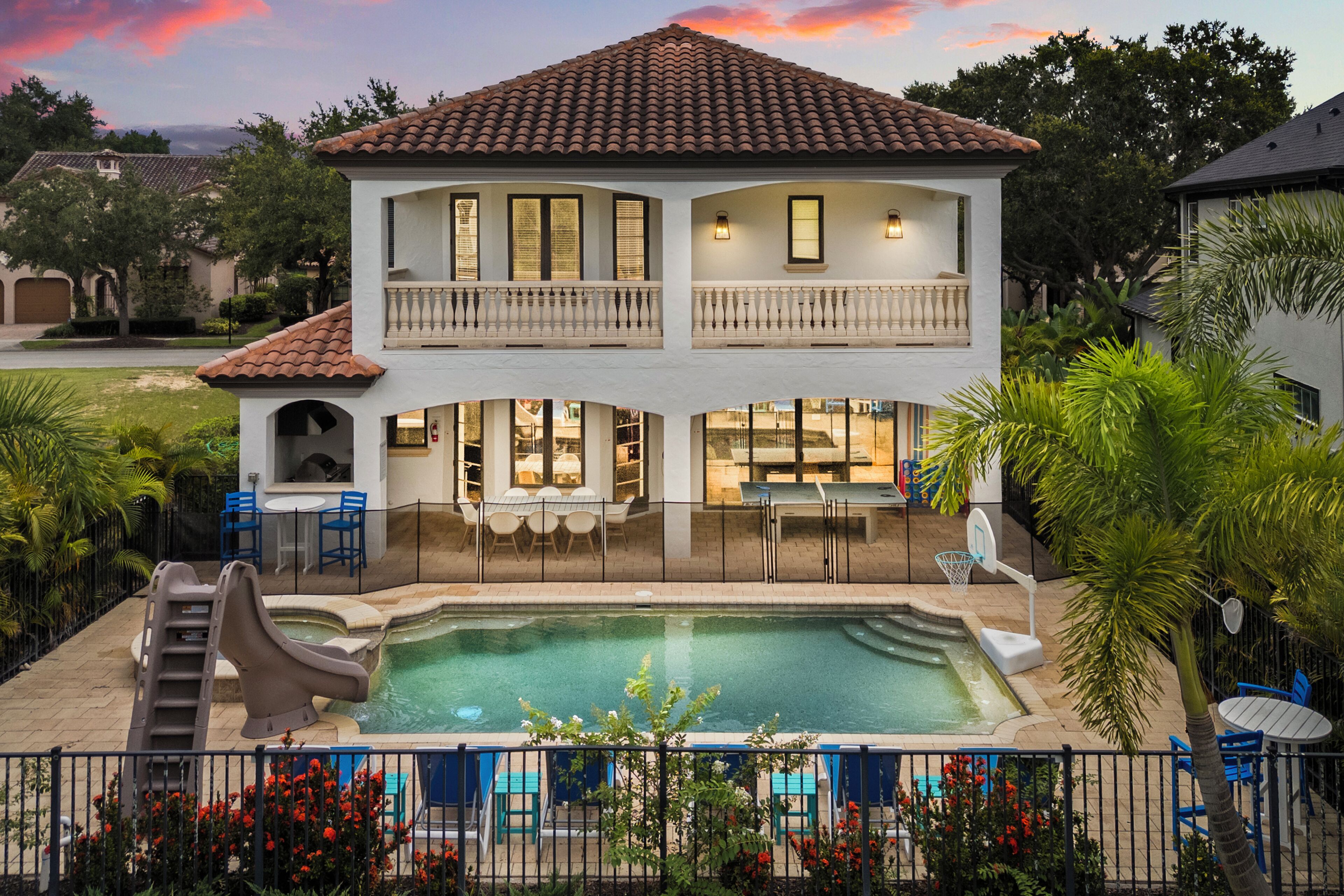 A two-story house with a swimming pool, outdoor seating, and a slide.