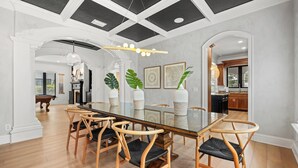 Un comedor con una mesa de vidrio, sillas de madera y un techo con paneles blanco y negro.