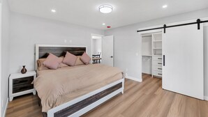 Une chambre à coucher moderne avec un lit, une table de chevet et un dressing.