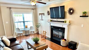 Una sala de estar con chimenea, televisor y ventilador de techo.