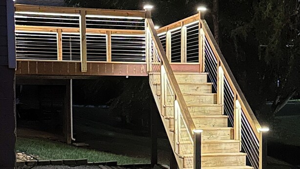Una escalera de madera que conduce a un espacio exterior techado con barandilla.