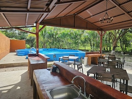 An outdoor pool area with a bar and seating under a covered pavilion.