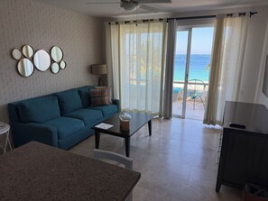 Relax in this stylish living room with a sofa, coffee table, and flat-screen TV, offering a view of the ocean from the balcony.