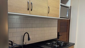 A modern kitchen with wooden cabinets, a black countertop, a stainless steel sink, and a built-in microwave. - FLAT IN ALTER DO CHÃO (Alter do Chão)