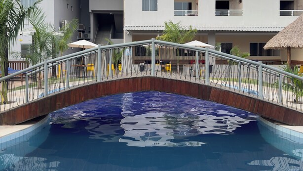 A swimming pool with a wooden bridge, surrounded by buildings with balconies and air conditioning units. - FLAT IN ALTER DO CHÃO (Alter do Chão)