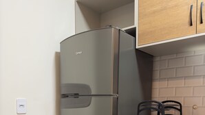 A compact kitchen with a stainless steel refrigerator, wooden cabinets, and a black countertop. - FLAT IN ALTER DO CHÃO (Alter do Chão)