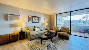 A living room with a sofa, armchairs, a coffee table, and a large window.