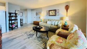 A living room with a sofa, a coffee table, a patterned rug, and a bookshelf.