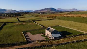 A rural landscape with a stone house surrounded by fields and stone walls.