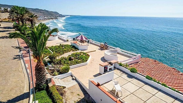 Une terrasse sur le toit avec une piscine, des espaces de détente en plein air et une vue sur l’océan.