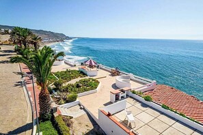 Eine Dachterrasse mit Pool, Sitzgelegenheiten im Freien und Blick auf das Meer.