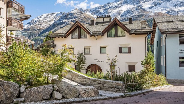 A traditional chalet-style building with a stone facade, wooden balconies, and a stone staircase leading to the entrance. - Chesa Trais Dschembers by Interhome (Champfer)