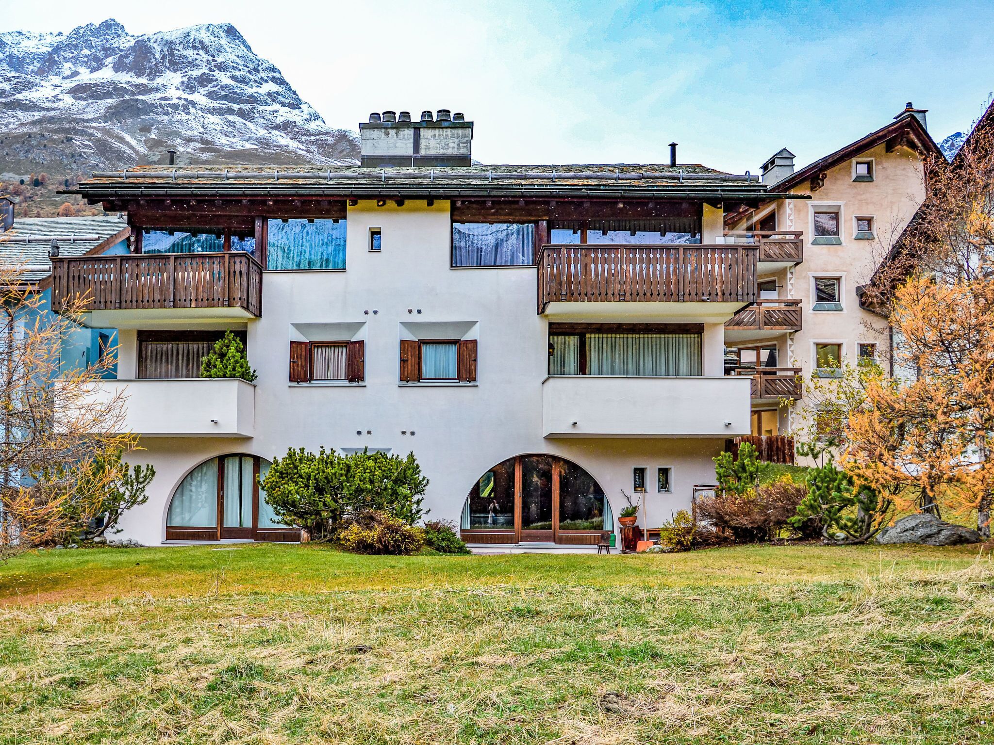 Un immeuble à deux étages doté de balcons, de grandes fenêtres et surplombant un paysage montagneux.