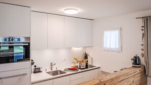A modern kitchen with white cabinets, a Bosch oven, a sink, and a wooden countertop.