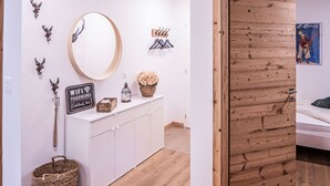 A room with a white cabinet, a round mirror, a wooden door, and a poster on the wall.