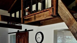 Een landelijke keuken met een houten tafel, een klok en uitzicht op buiten.