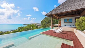 A luxurious infinity pool with a wooden deck, a covered seating area, and a view of the ocean. -  Jasmine Waterslide Villa (Koh Samui)