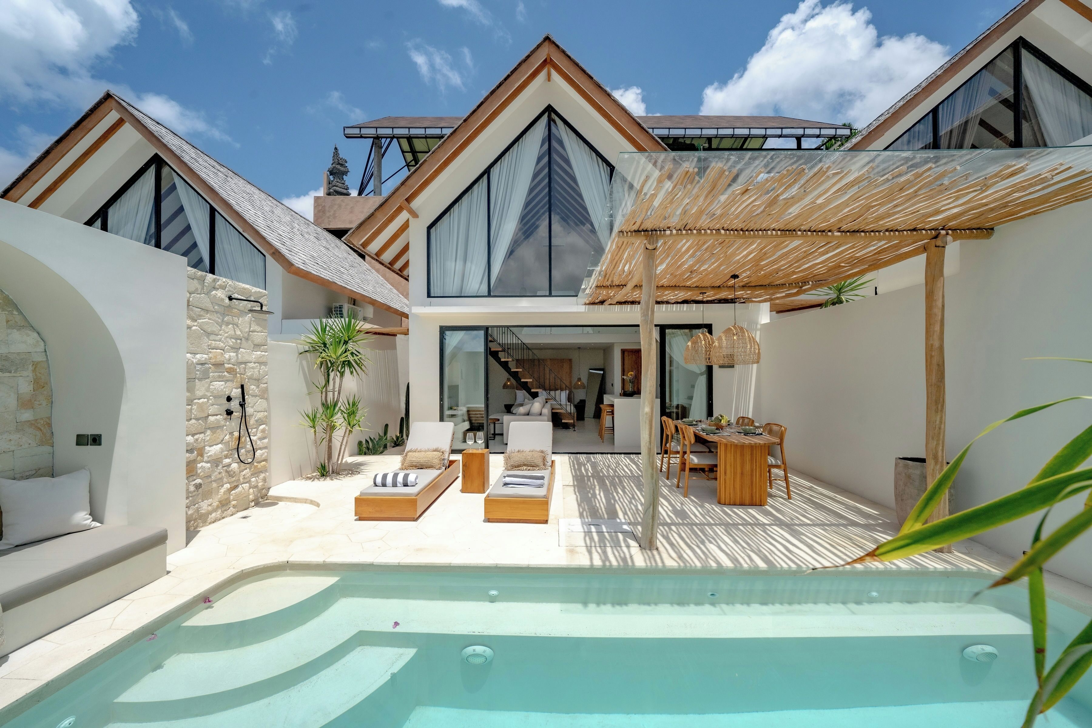 Eine moderne Villa mit Swimmingpool, Sitzgelegenheit im Freien und Blick ins Innere.