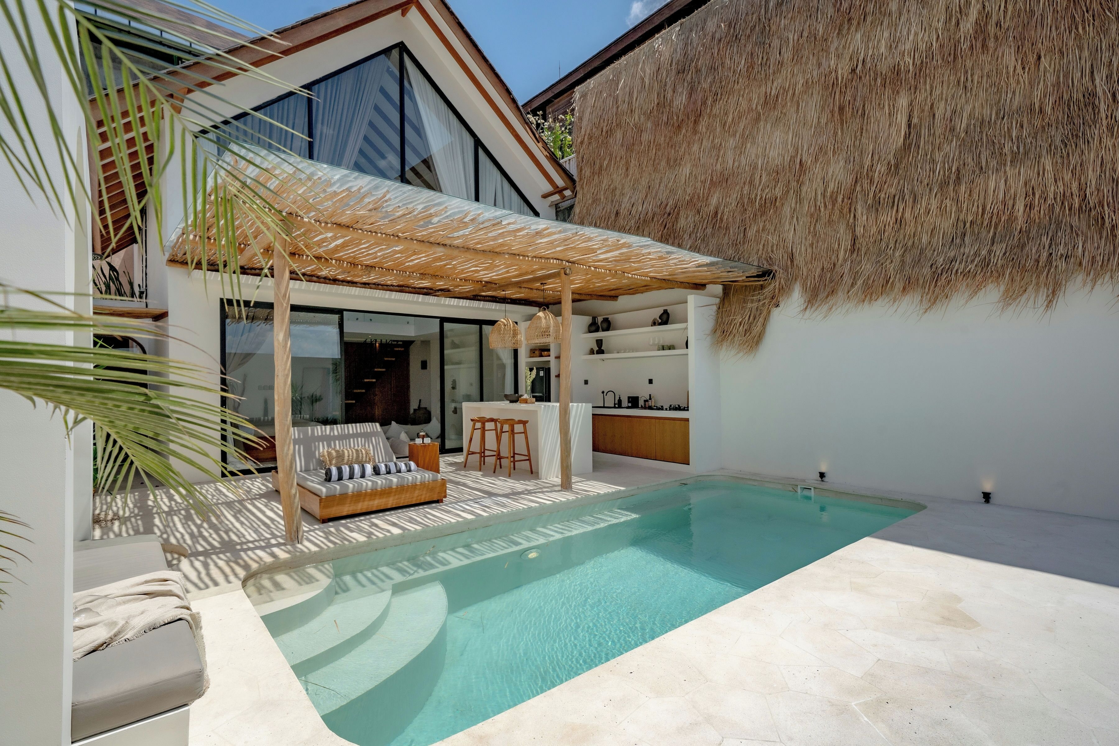 Une maison moderne dotée d’une piscine, d’un patio couvert et d’un espace cuisine.