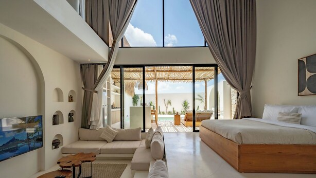 A spacious bedroom with a large bed, a sofa, and a TV. - 7Seas Bingin (Pecatu)