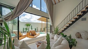 A modern living room with a pool view, a staircase, and a variety of plants. - 7Seas Bingin (Pecatu)