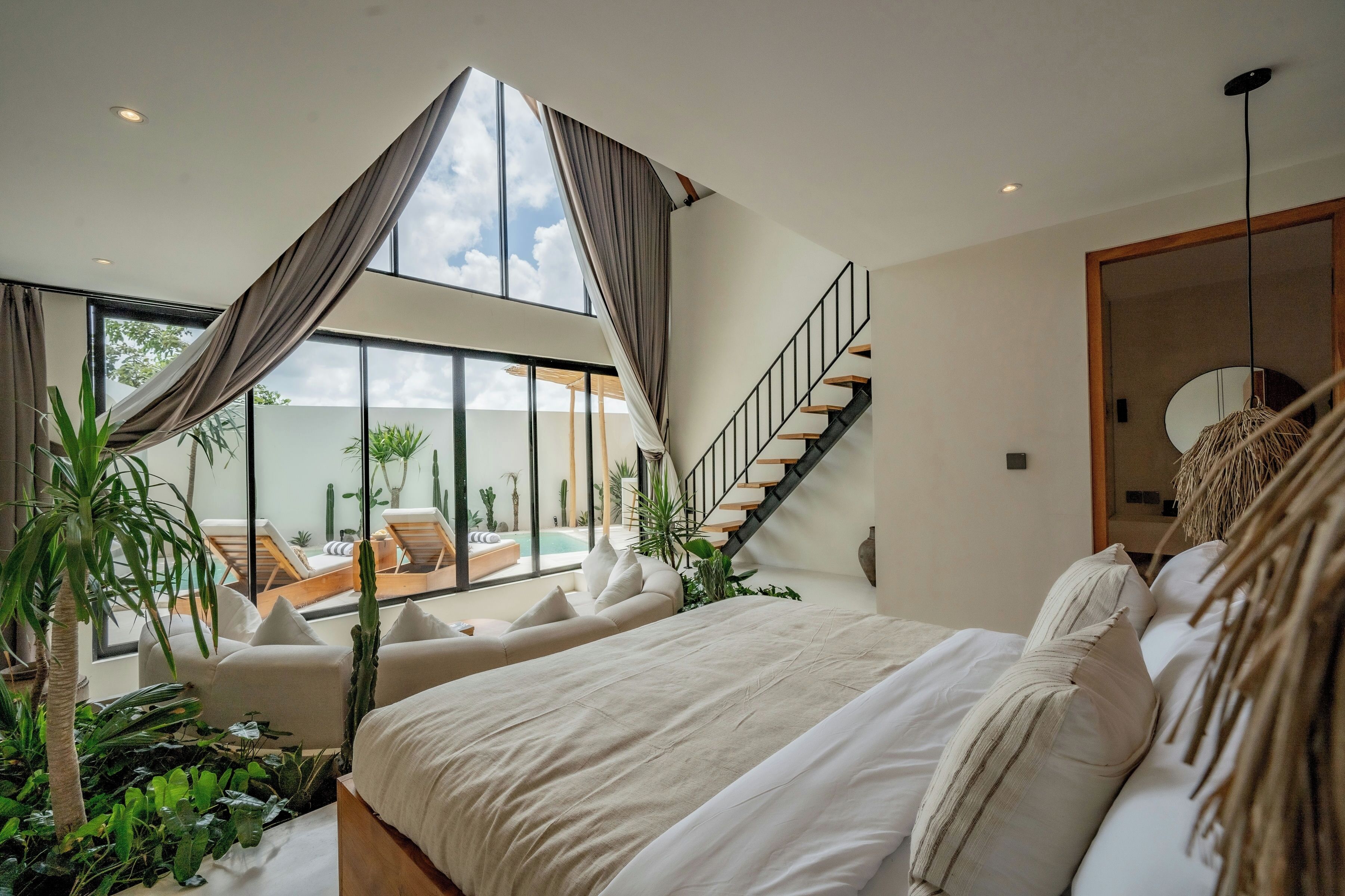 Un dormitorio con una cama grande, una escalera y vistas a una piscina y zona de estar exterior.