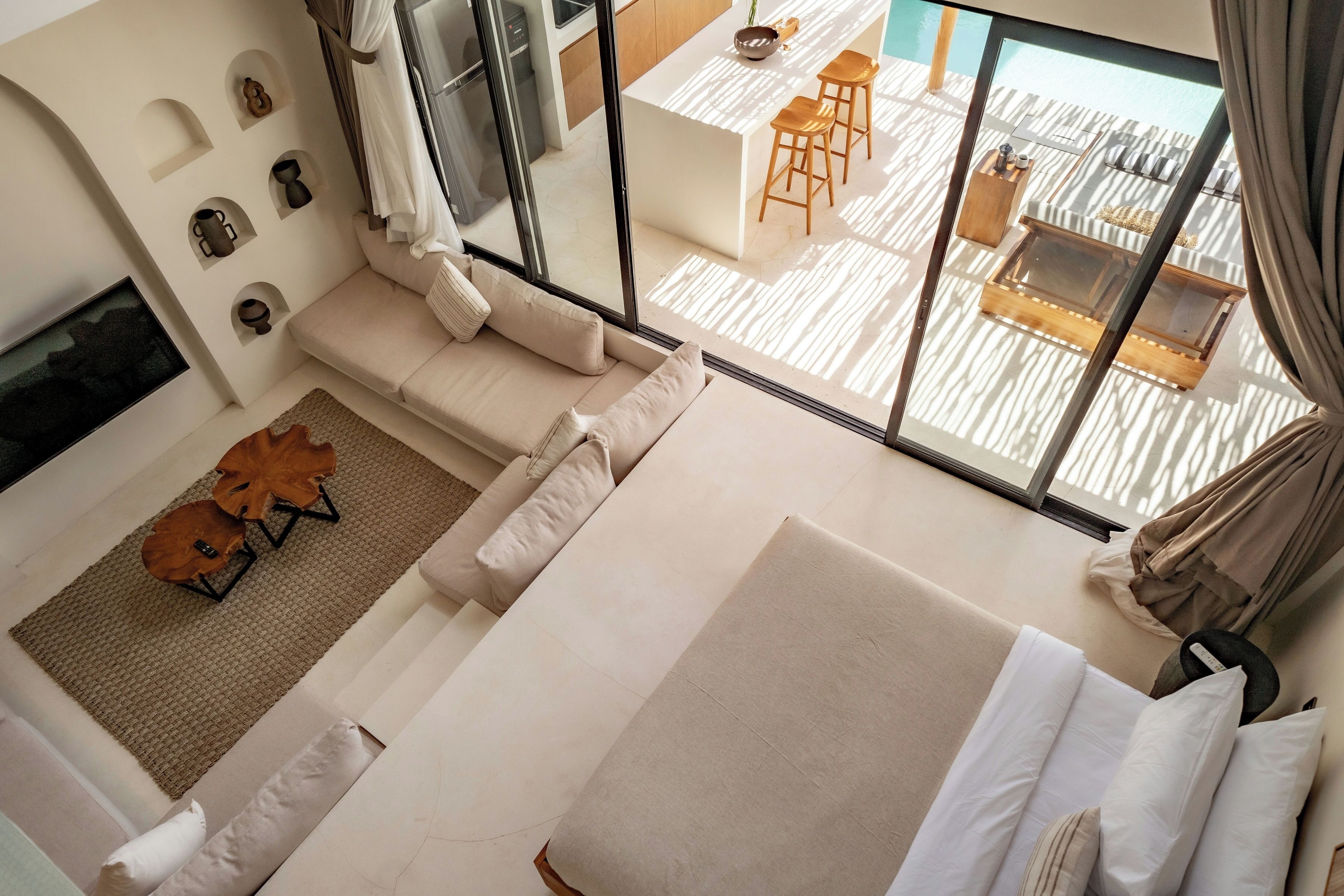Ett modernt hotellrum med en stor säng, en soffa, en matplats med barstolar och utsikt över den utomhusbelägna terrassen.