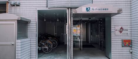 Ein Gebäudeeingang mit einem Schild, das einen Parkplatz, einen Fahrradständer und einen Trinkbrunnen anzeigt.