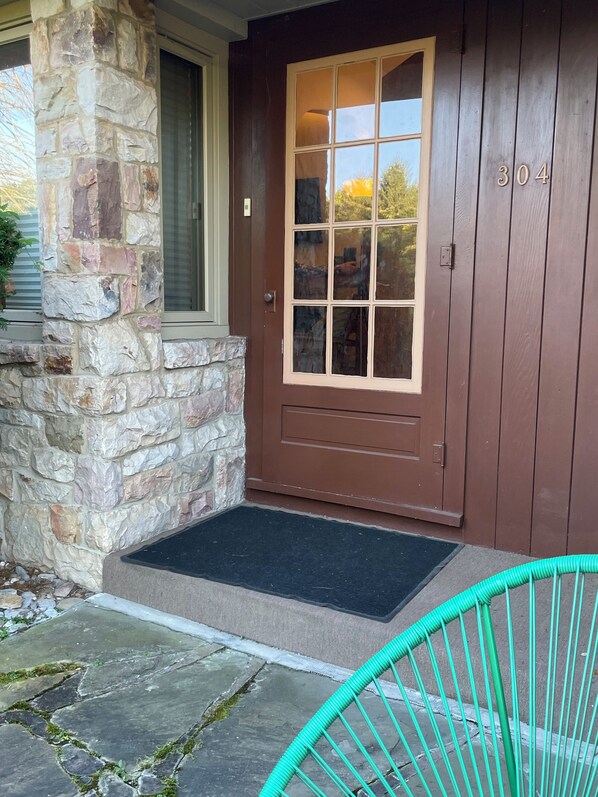 A stone and wood exterior with a brown door, a mailbox, and a green chair. - Historic 3bd/2ba home in State College-Walk everywhere WiFi “Lucky Rabbit Lodge” (State College)