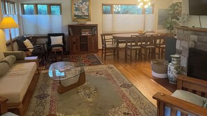 Un salon comprenant un canapé, une table basse, un tapis, une table à manger, des chaises et une cheminée.
