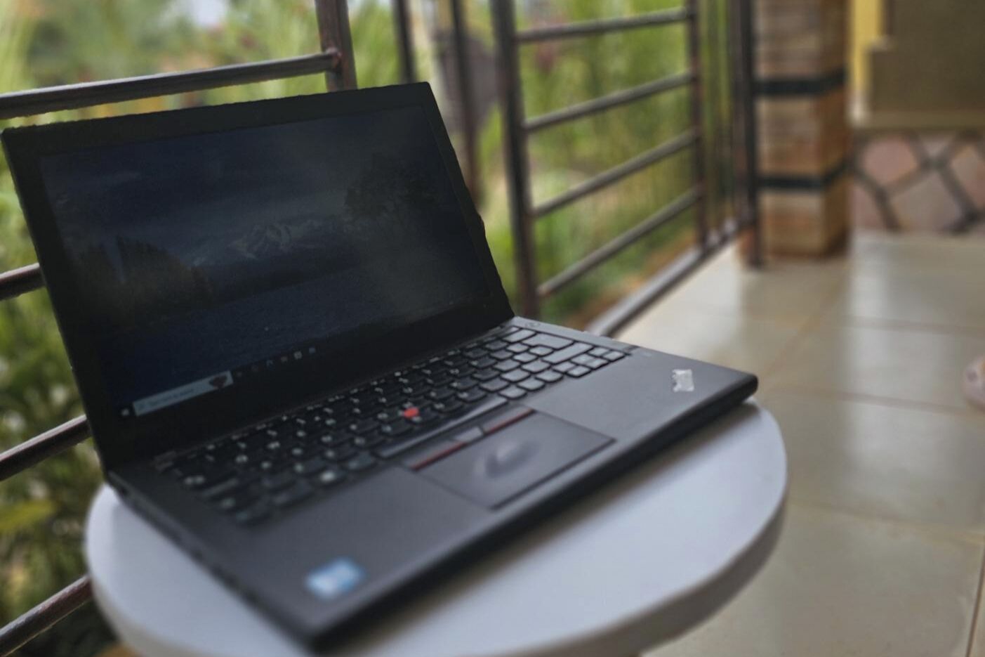 Ein Laptop auf einem kleinen runden Tisch mit Blick auf eine grüne Landschaft.
