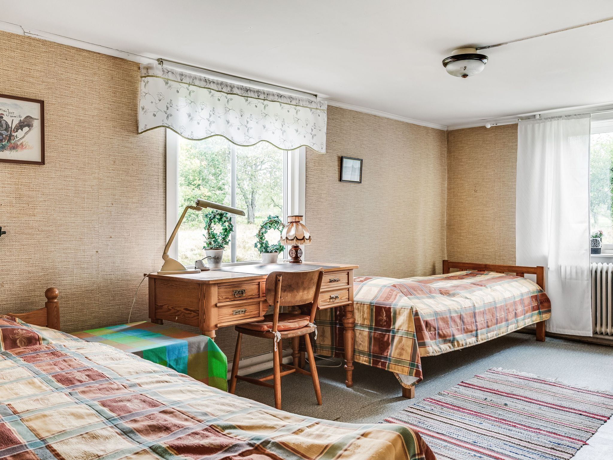 A bedroom with two beds, a desk, and a chair.