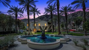 A fountain surrounded by palm trees and a building with illuminated windows. - Legacy Villas Near Main Pool Ground Floor Kitchen Resort#A (La Quinta)