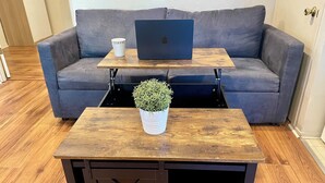 A modern living room with a grey sofa, a wooden coffee table with a plant, a laptop, and a coffee cup. - Sunnyvale Cabin (Sunnyvale)