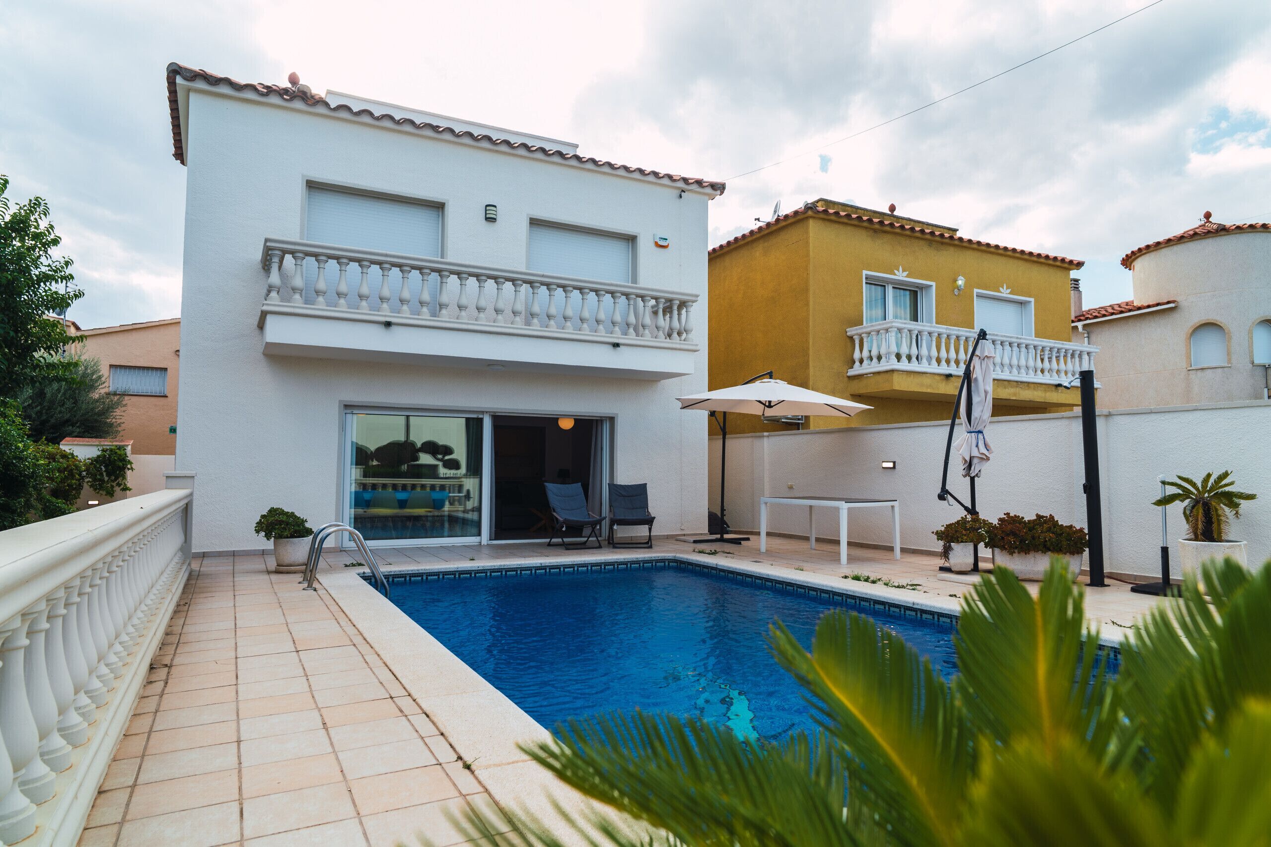 A residential building with a swimming pool, a balcony, and a patio area with outdoor furniture.