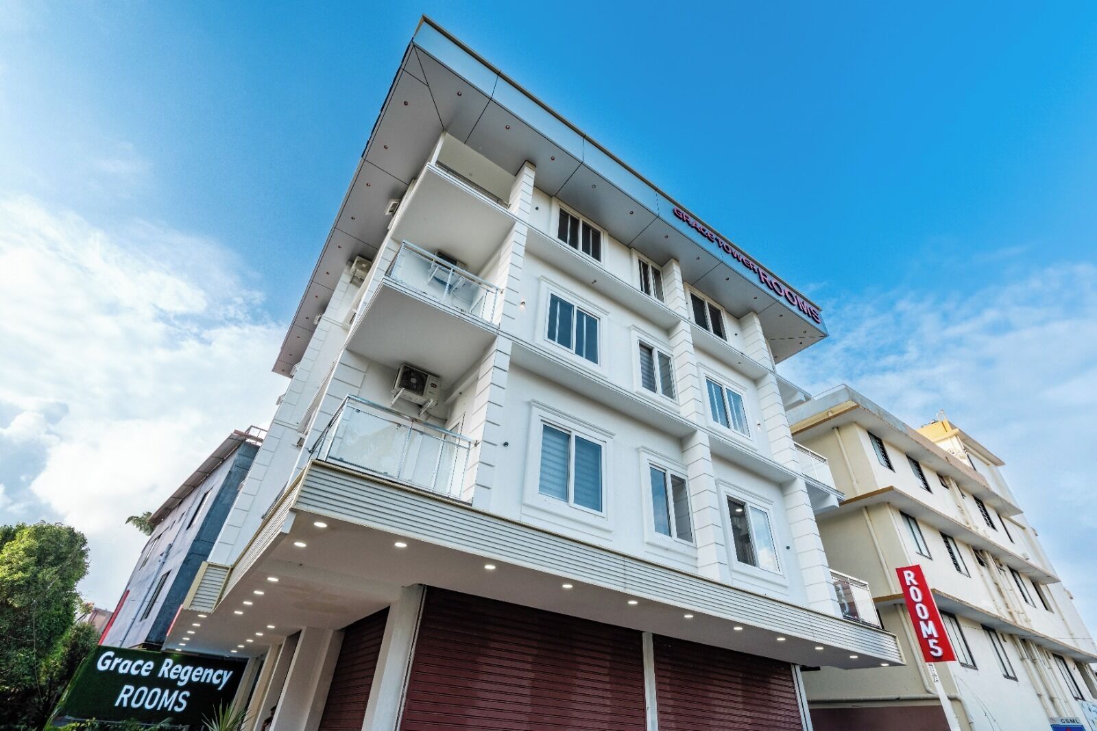 A multi-story hotel with a sign indicating "Grace Regency Rooms" and a "Rooms 5" sign.