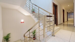 A modern interior with a glass and metal staircase, white walls, and a clean, minimalist design. - Grace Regency (Kanayannur)