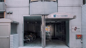 A building entrance with a sign indicating a parking area, a bicycle rack, and a water fountain. - Minimalist Loft 301 (Osaka)
