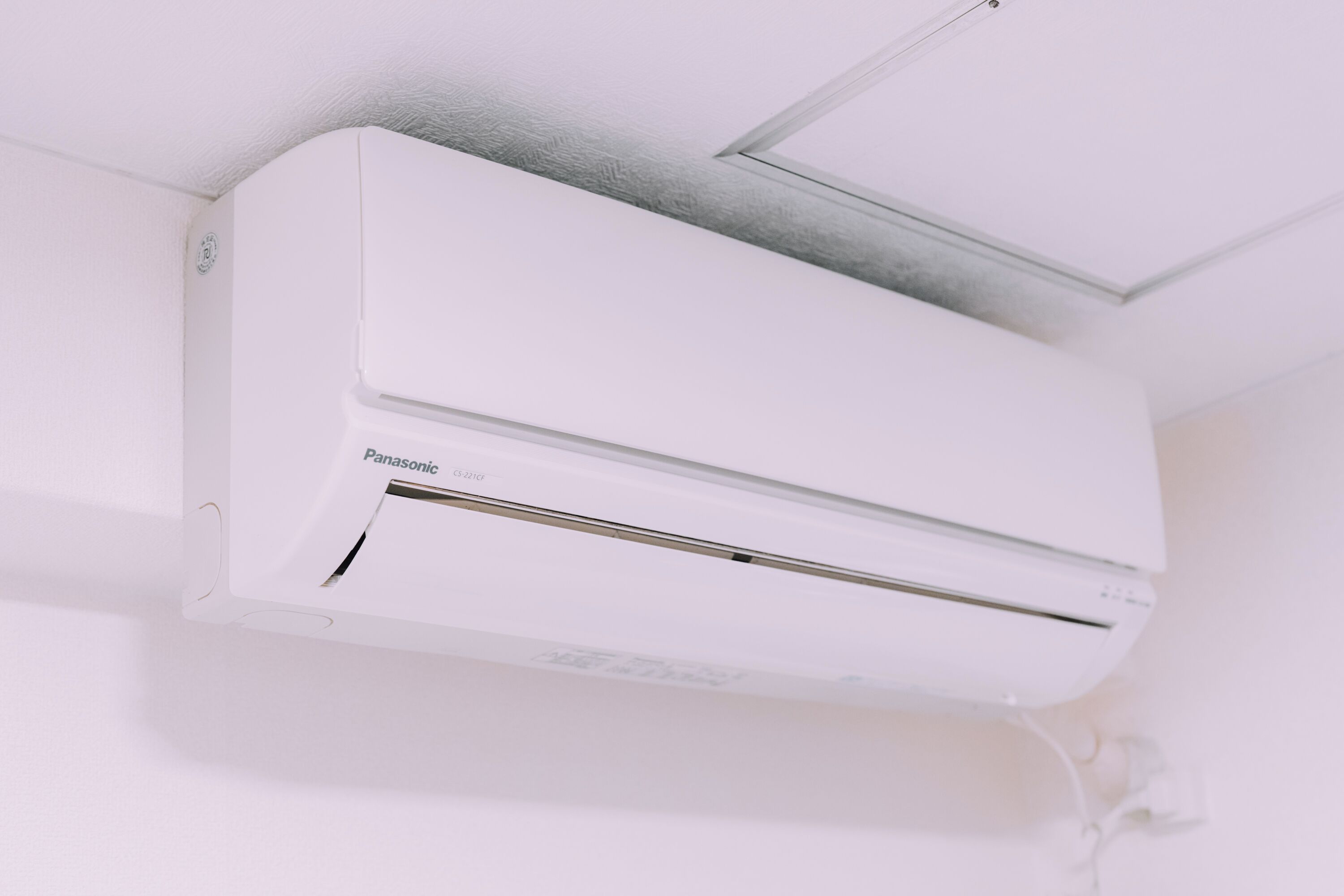 A white Panasonic air conditioner mounted on a ceiling.